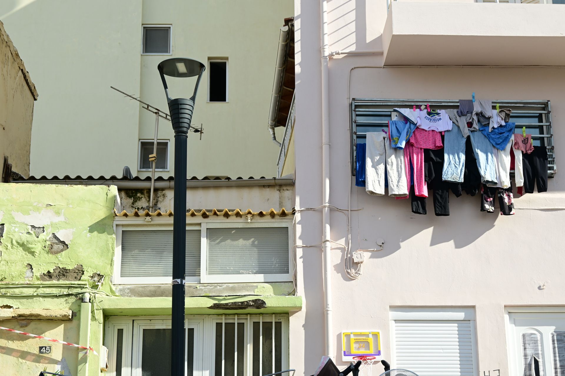 Adjoining building facades with a street lamp and laundry hanging outside a window