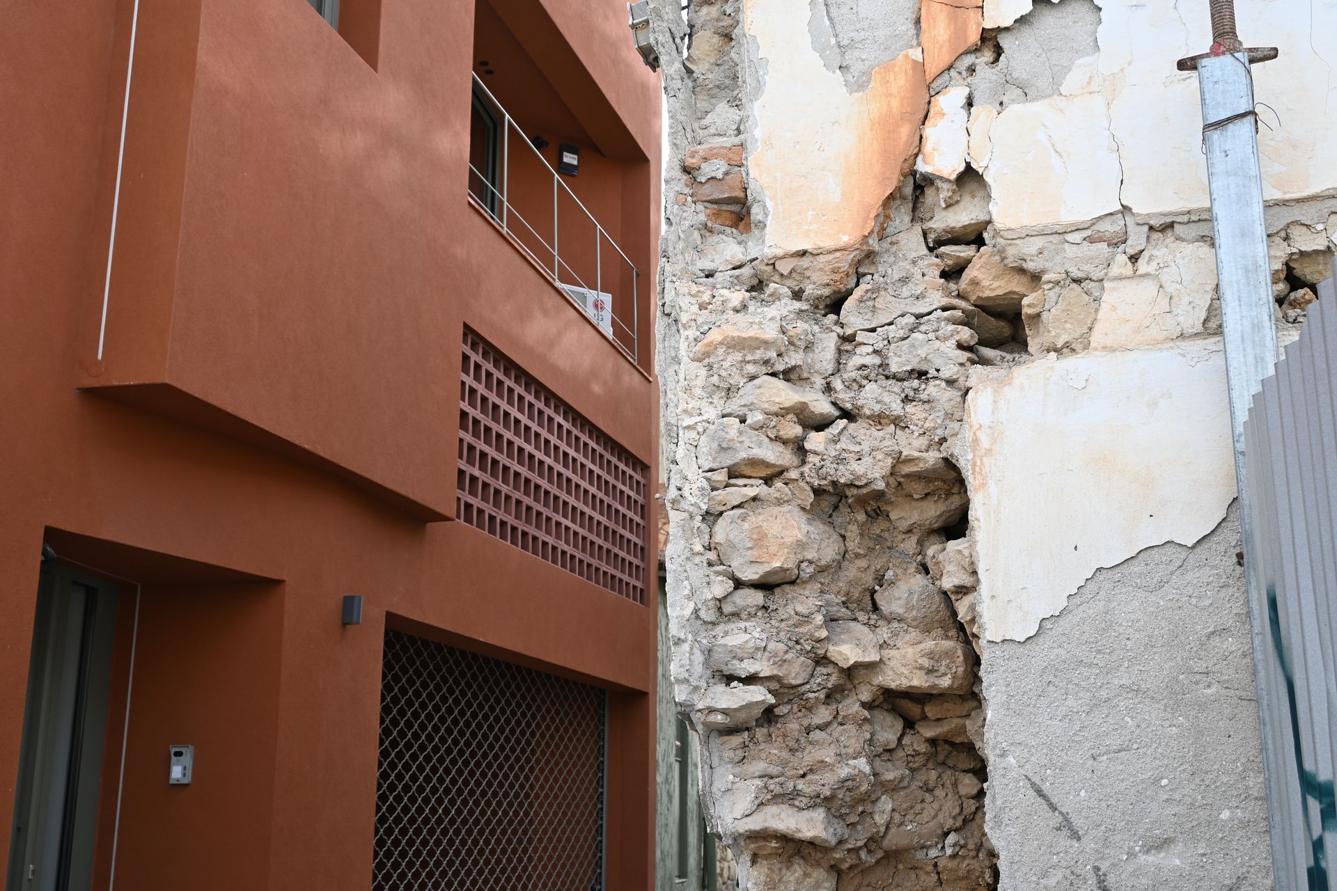 Orange building beside an exposed stone wall with broken plaster